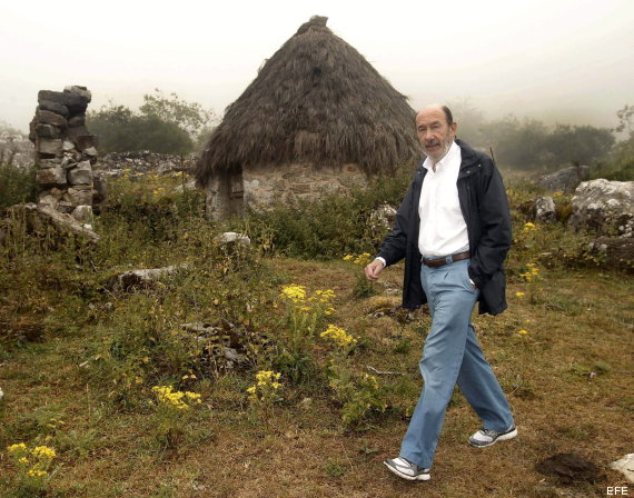 GRA130 VILLAR DE VILDAS, 13/08/2013.- El secretario general del PSOE, Alfredo Pérez Rubalcaba, pasea ante un "teitos", antiguas construcciones ganaderas con los techos de paja en Villar de Vildas, una pequeña localidad de montaña del suroccidente de Asturias en la que se ha reunido con ganaderos y ha visitado el Parque Natural de Somiedo Rubalcaba, ha acusado hoy al PP de tener "abandonadas" las políticas para el medio rural a corto y medio plazo y de poner en peligro los ayuntamientos de este ámbito con una reforma de la administración local que puede dejar sin servicios sociales a los núcleos más pequeños. EFE/Alberto Morante